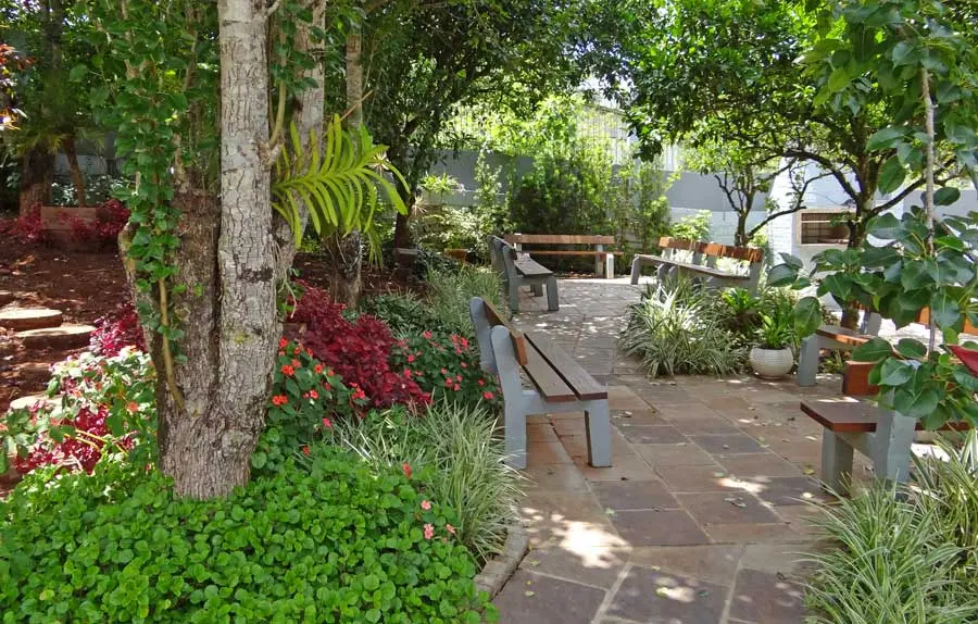 Bancos e cadeiras em jardim com árvores frutíferas