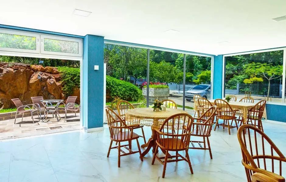 Refeitório envidraçado do Serraville com mesas de madeira junto ao jardim