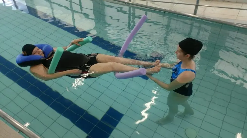Sessão de fisioterapia aquática na piscina terapêutica do Serraville, com paciente em flutuação assistida por fisioterapeuta