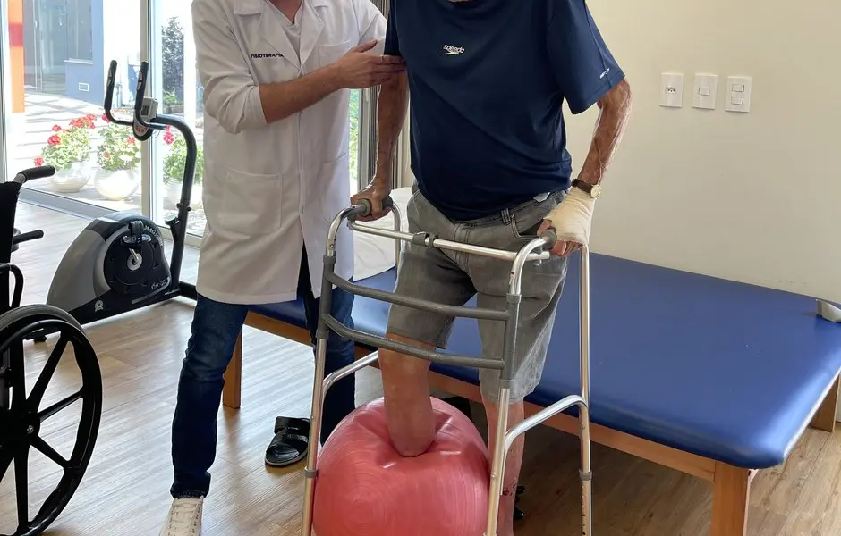 Treino de marcha com fisioterapeuta durante reabilitação pós-operatória em internação geriátrica