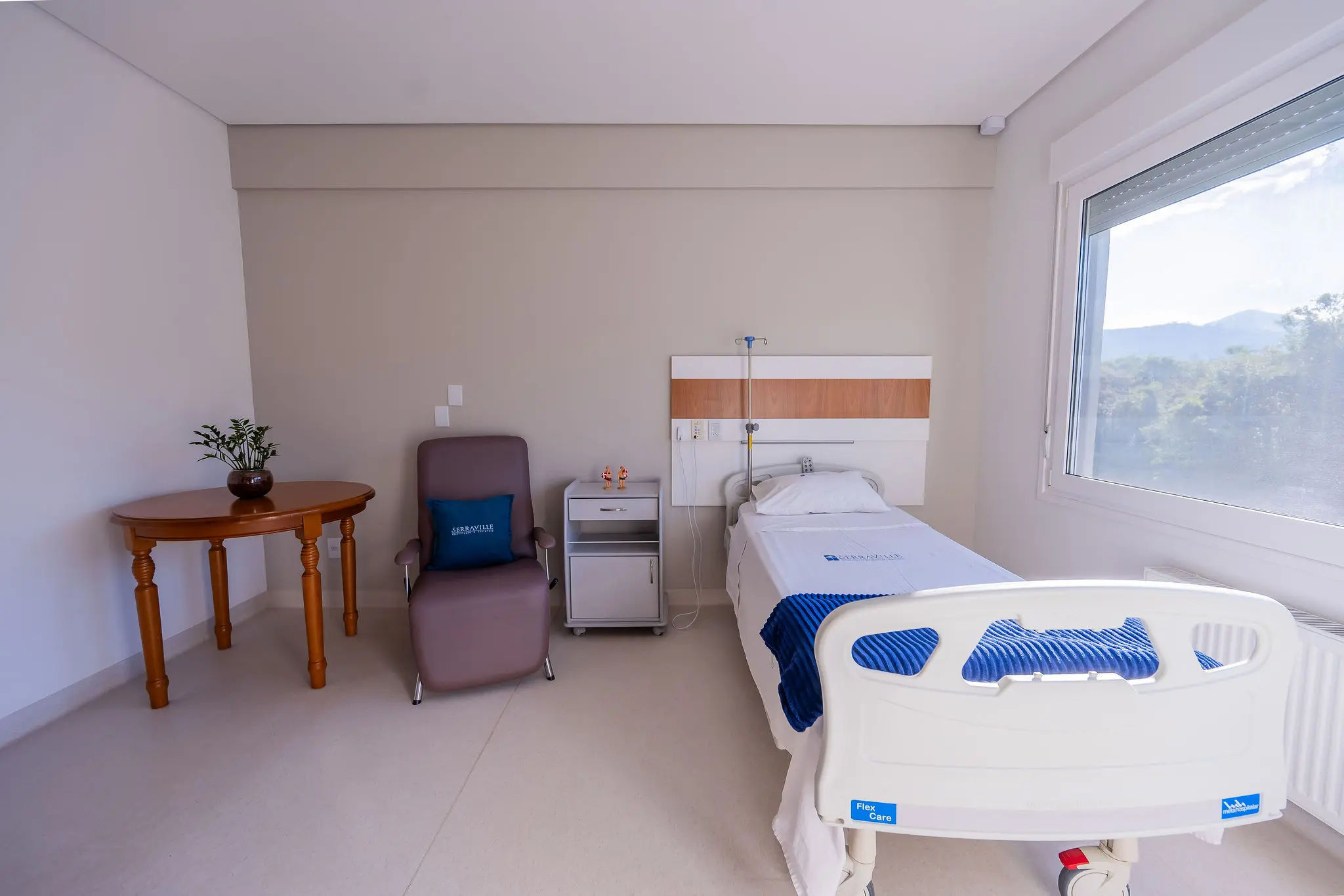 Acomodação clara com cama hospitalar e janela