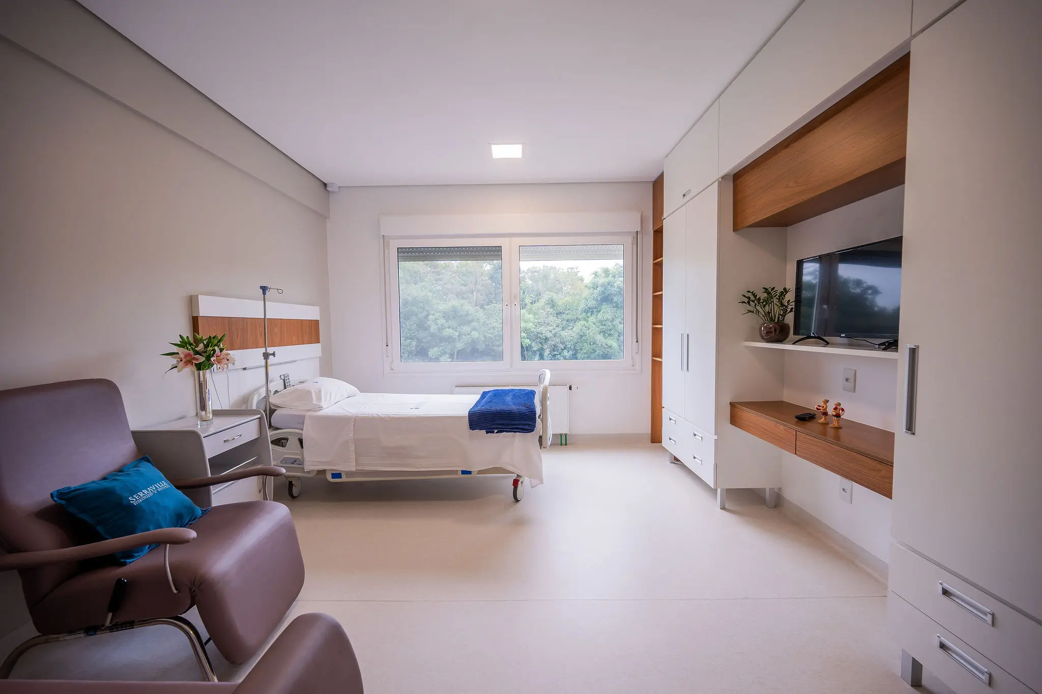 Suíte ampla com cama hospitalar, poltrona e janela