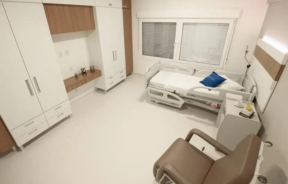 Quarto de internação do Serraville com cama hospitalar elétrica e poltrona de descanso